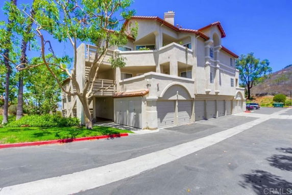 Front view of a multi-story building with balconies and multiple garage doors.