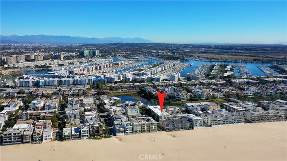 Aerial view of a coastal residential area with buildings near the beach and a marina.