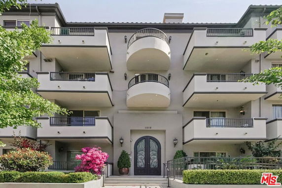 Front view of a multi-story residential building with multiple balconies and a decorative entrance.