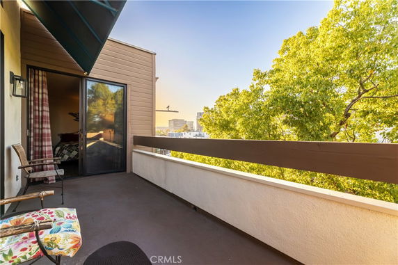 Balcony area overlooking a city with a view of trees and buildings.