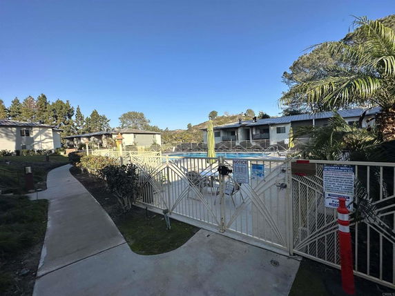 Outdoor swimming pool area with surrounding apartments and trees.
