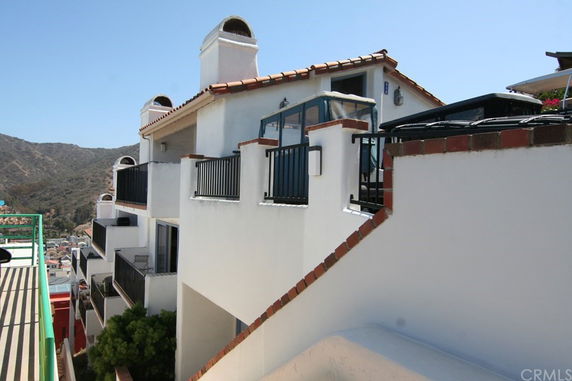 Front view of a multi-story building with balconies and a sloped roof.