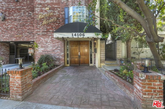 Front view of a multistory brick building with a large entrance and a black canopy.