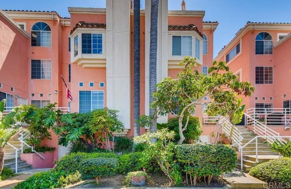 Front view of a multi-story building with a central staircase and a pink exterior.