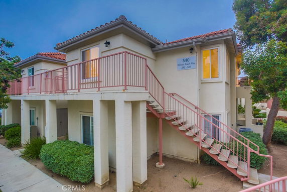 Front view of a two-story building with exterior stairs and a balcony.