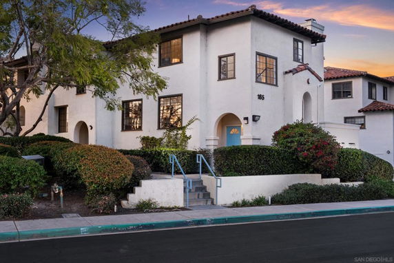 Front view of a multi-story house with stucco exterior and tiled roof.