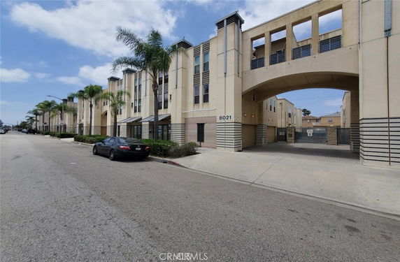 Front view of a multi-story building with an archway and palm trees.