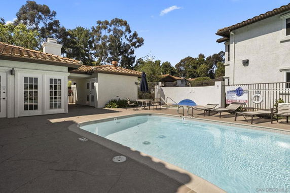 Outdoor swimming pool area with a building featuring French doors and outdoor seating.