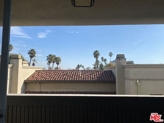 View of rooftops with palm trees and a clear sky.