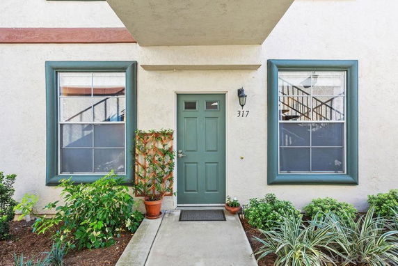 Front view of a building entrance with plants on either side.