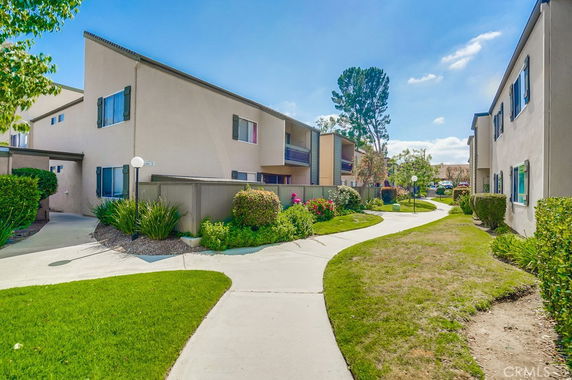 Front view of a two-story apartment building with pathways and landscaped areas.