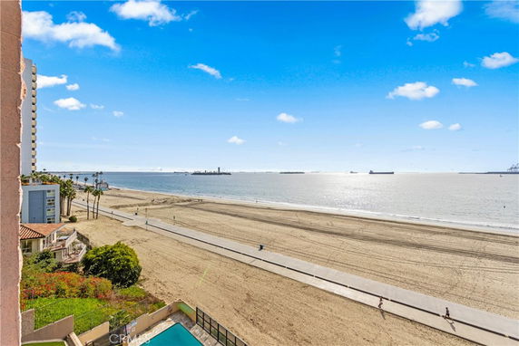Panoramic view of a beachfront with buildings in the distance and ocean horizon.