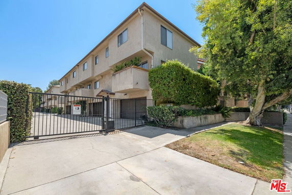 Front view of a multi-story building with gated entrance and driveway.