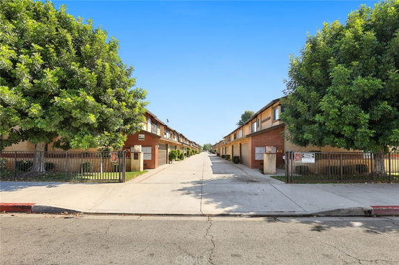 Front view of a two-story apartment building with symmetrical rows and gated entrances.