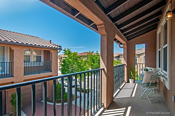 View from a balcony overlooking adjacent homes and a tree-lined street.