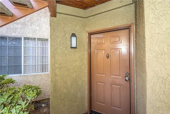 Entrance view of a house with a brown door and exterior light fixture.