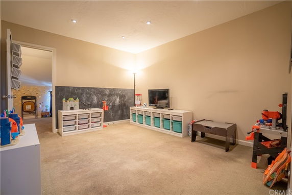 Room with play area setup, including a chalkboard, storage bins, and a small table.