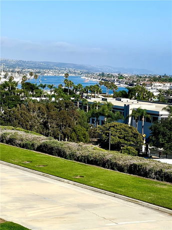 View of a coastal area with buildings, greenery, and a body of water in the distance.