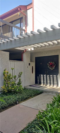 Front view of a house with a pergola over the entryway and a decorated door.