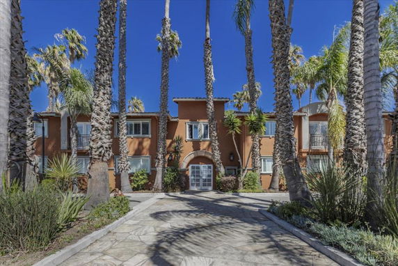 Front view of a two-story building with palm trees.