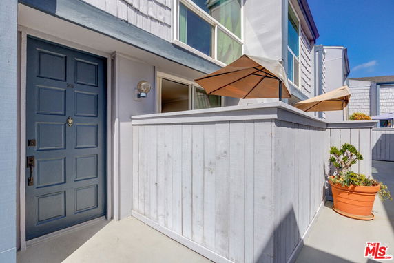 Front view of a two-story building with a blue door and a small patio area.
