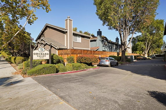 Front view of a multi-story residential building with Orchard Valley sign.