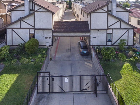 Front view of a residential building with a gated entrance and driveway.
