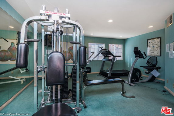 Room with exercise equipment including machines and a treadmill.