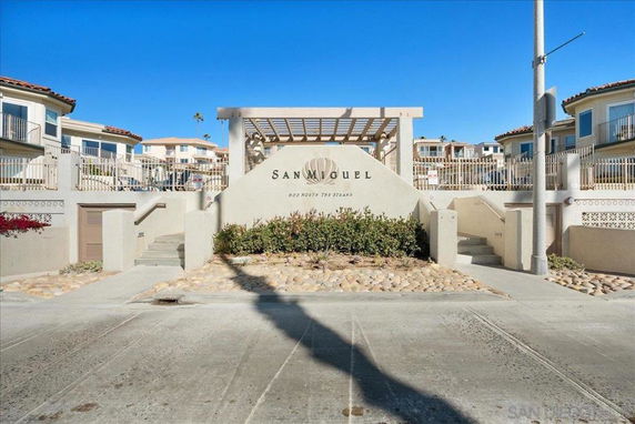 Front view of a residential building with a sign and stairs leading upward.