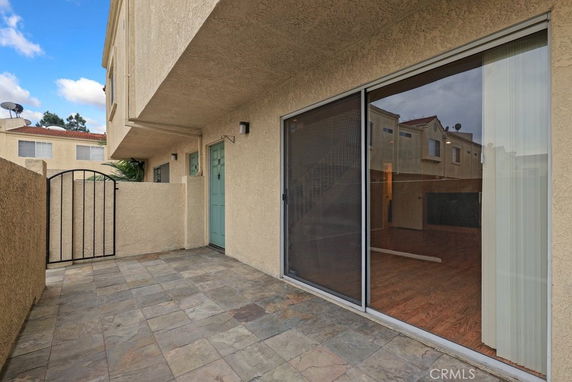 Front view of a building with a small patio area and sliding glass door.