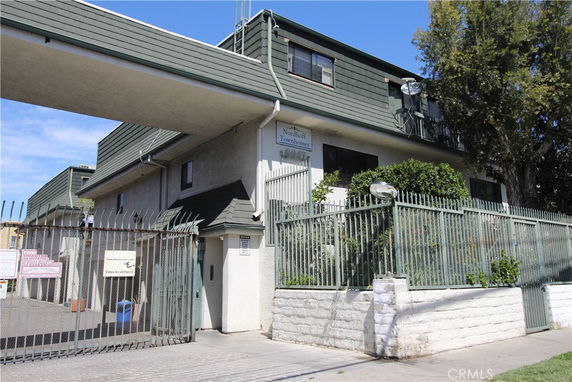 Front view of a multi-story building with a fence and gate.