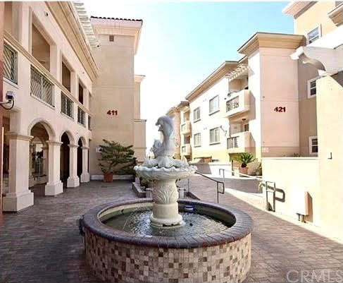 Front view of a multi-story building complex with decorative fountain.