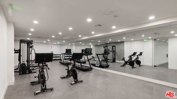 Indoor gym area with exercise equipment and mirrored wall.