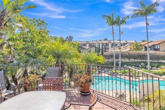 View of a pool and surrounding houses from a patio.