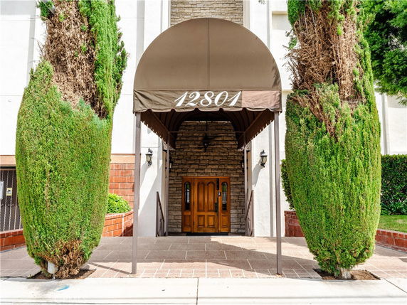 Front entrance of a building with an archway canopy and double wooden doors.