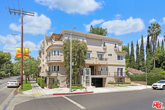 Front view of a multi-story residential building on a street corner.