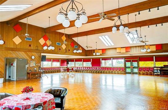 Spacious indoor room with wooden flooring and seating for events or recreation.