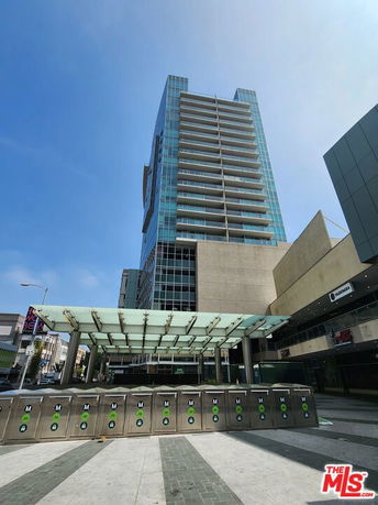 Front view of a modern high-rise building with glass facade and multiple balconies.