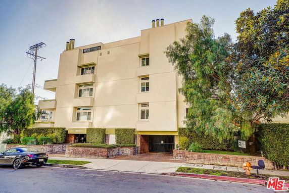 Front view of a multi-story residential building with a car parked in the foreground.