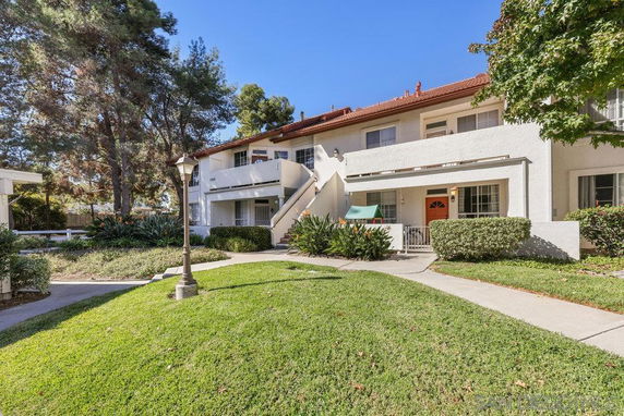 Front view of a two-story apartment building with exterior stairs and a landscaped lawn.