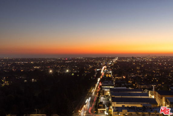 Panoramic nighttime view of a cityscape with a sunset sky.