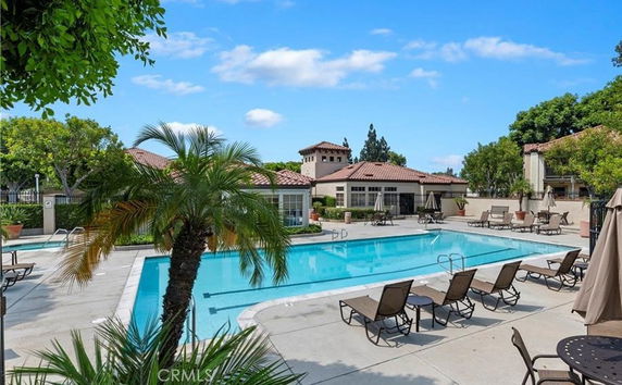 Outdoor swimming pool with surrounding lounge chairs and umbrellas.