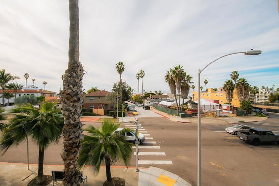 Street view with palm trees, buildings, and vehicles at an intersection.