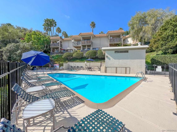 View of an outdoor swimming pool with lounge chairs and umbrellas.