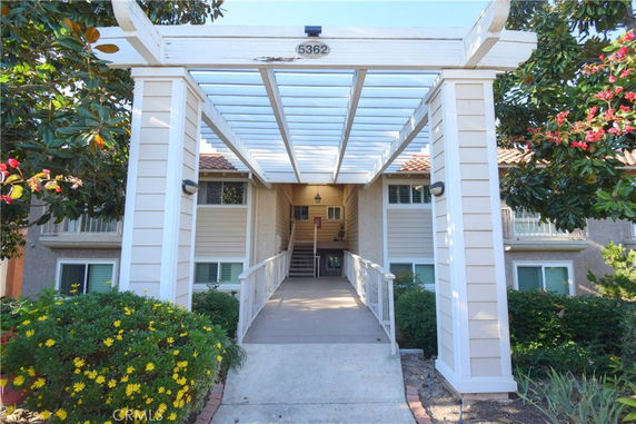 Front view of a two-story building with a pergola entrance.