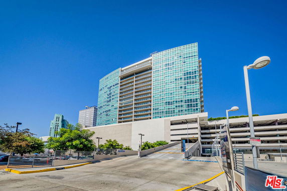 Front view of a multi-story glass building with adjacent parking structure.