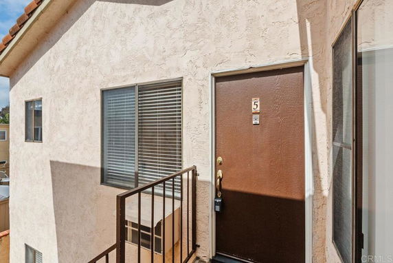 Exterior view of a building entrance with a brown door and windows.