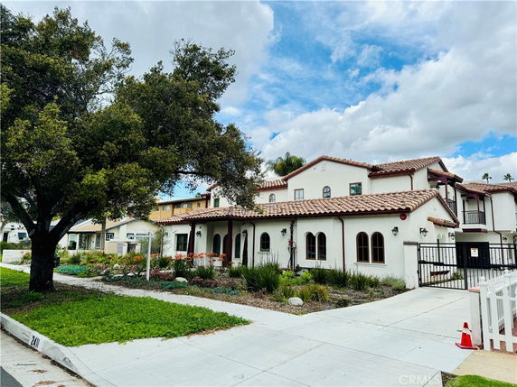 Front view of a two-story house with a red-tiled roof and arched windows.