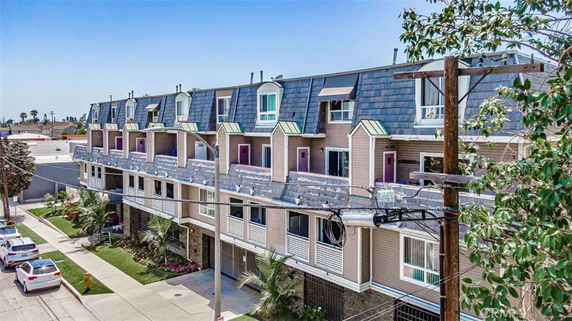 Front view of a multi-story residential building with balconies and a sloped roof.