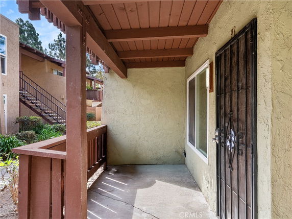 Front view of a building entrance with a metal security door and wooden railing.